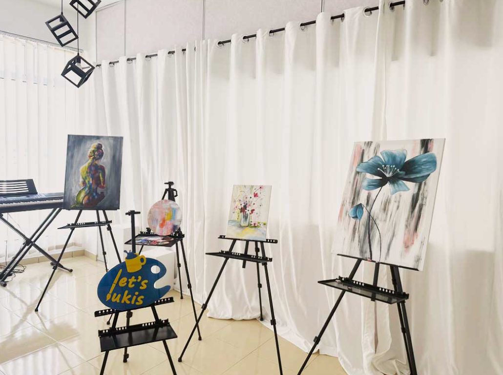 Bright art studio with easels, paint brushes and colourful canvases